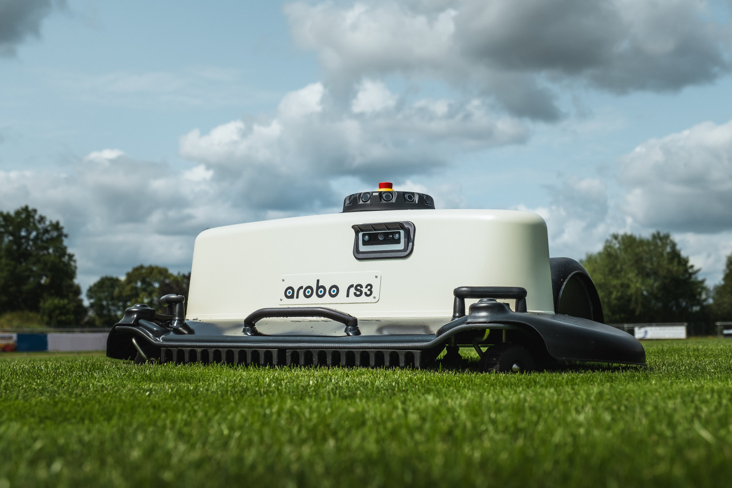 Der Arobo RS3 Mähroboter auf dem Rasen eines Sportplatzes.